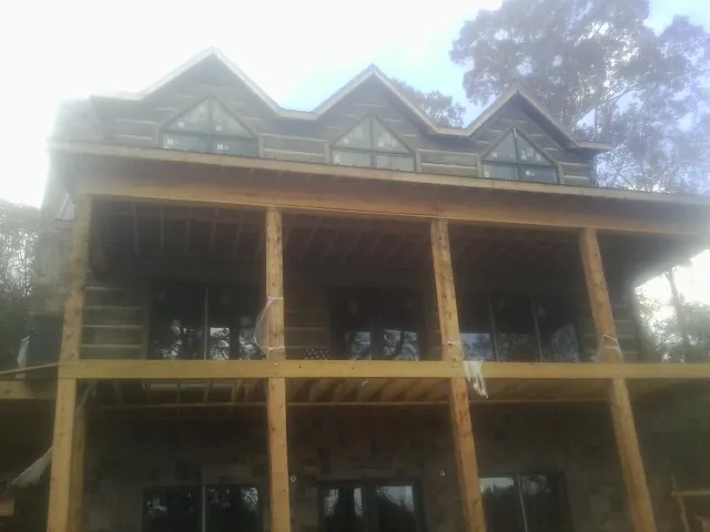 Dormers and porch framing on a large log home under construction — Roof Coating work by our crew in Palmyra
