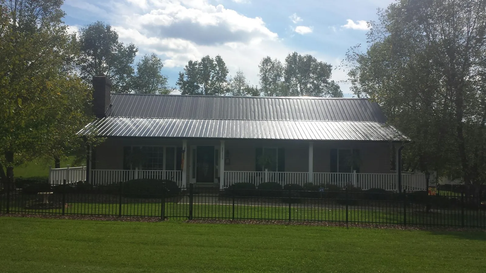 Gray metal roof on a brick ranch with a full width front porch — Gutter Guard Installation work by our crew in Palmyra