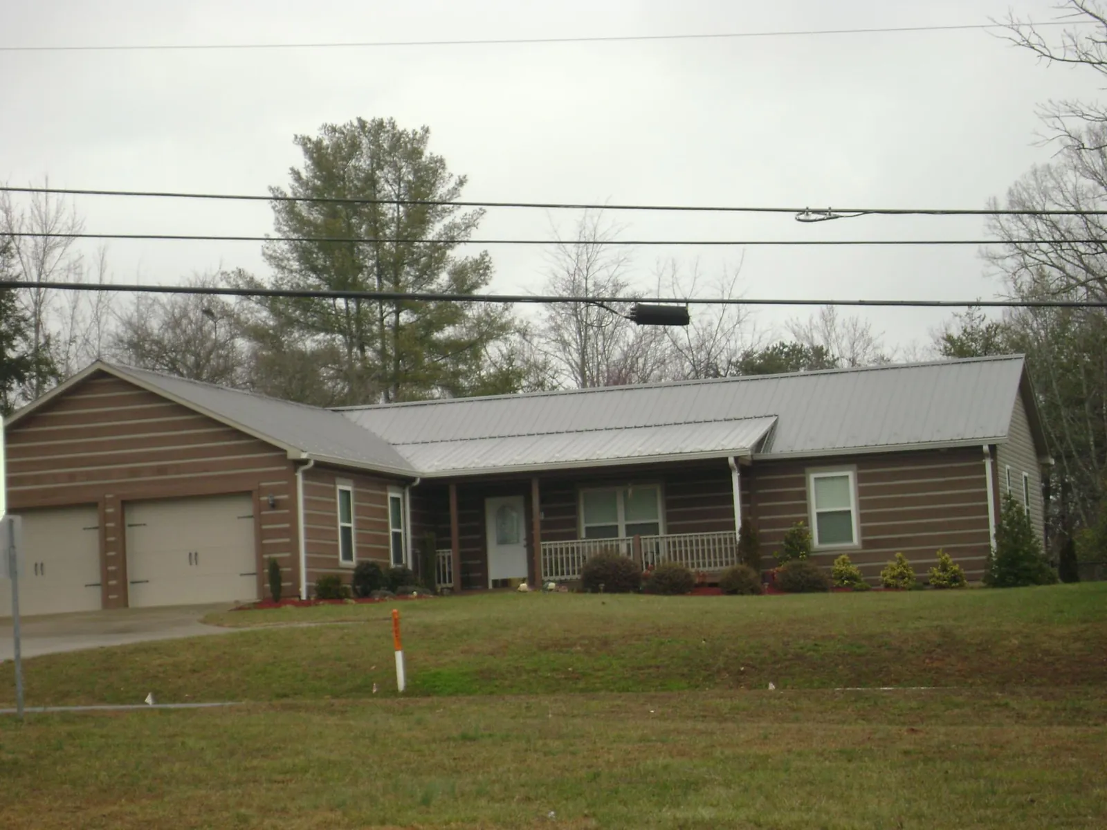 Gray metal roof on a log sided ranch home with a front porch in Palmyra